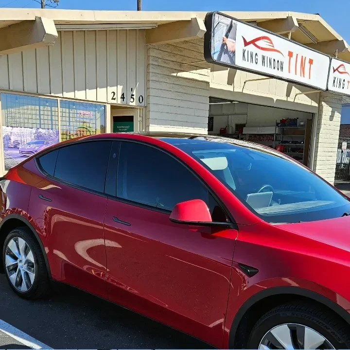 Red Tesla Model Y with freshly tinted windows, parked in front of King Window Tint at 2450 Fulton Ave, Sacramento