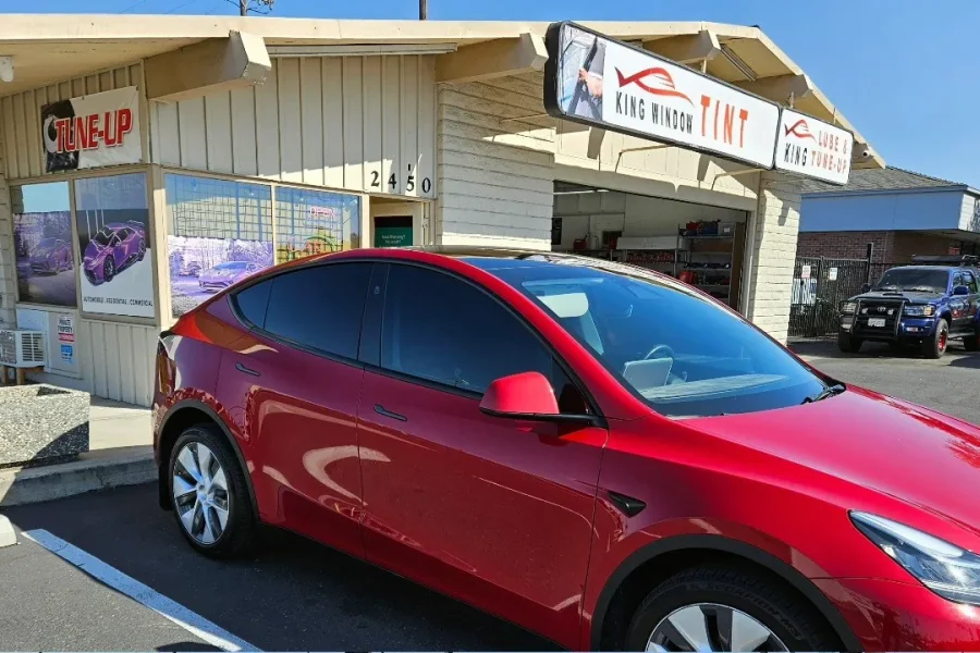 Red Tesla Model Y with freshly tinted windows, parked in front of King Window Tint at 2450 Fulton Ave, Sacramento
