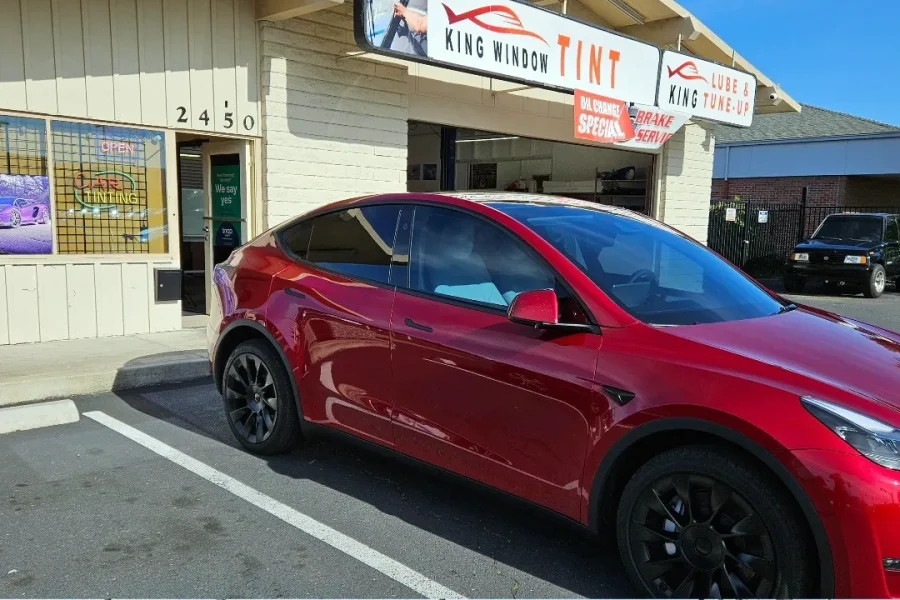 Red Tesla Model Y with freshly tinted windows, outside the King Window Tint shop on Fulton Ave in Sacramento