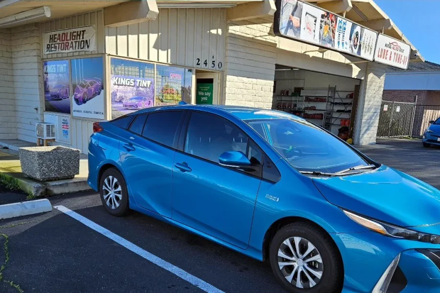 Blue Toyota Prius Prime with freshly tinted windows, outside the King Auto Tint shop on Fulton Ave in Sacramento