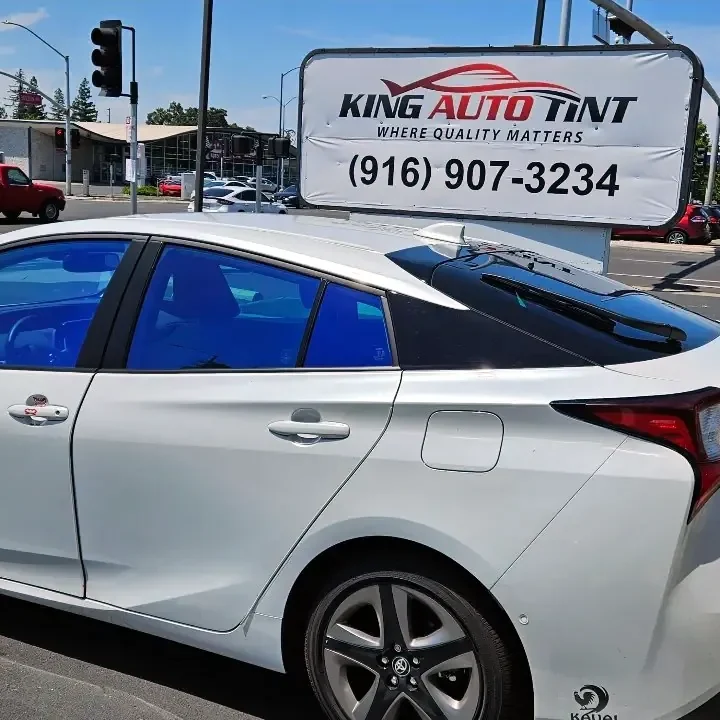 White Toyota Prius with freshly tinted windows, parked in front of King Auto Tint at 2450 Fulton Ave, Sacramento (blue-hued window film)