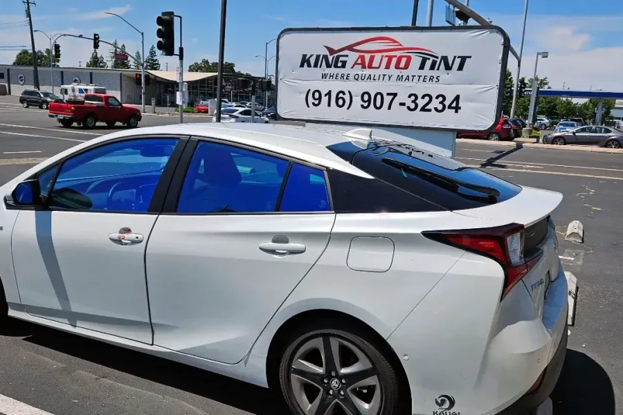 White Toyota Prius with freshly tinted windows, parked in front of King Auto Tint at 2450 Fulton Ave, Sacramento (blue-hued window film)
