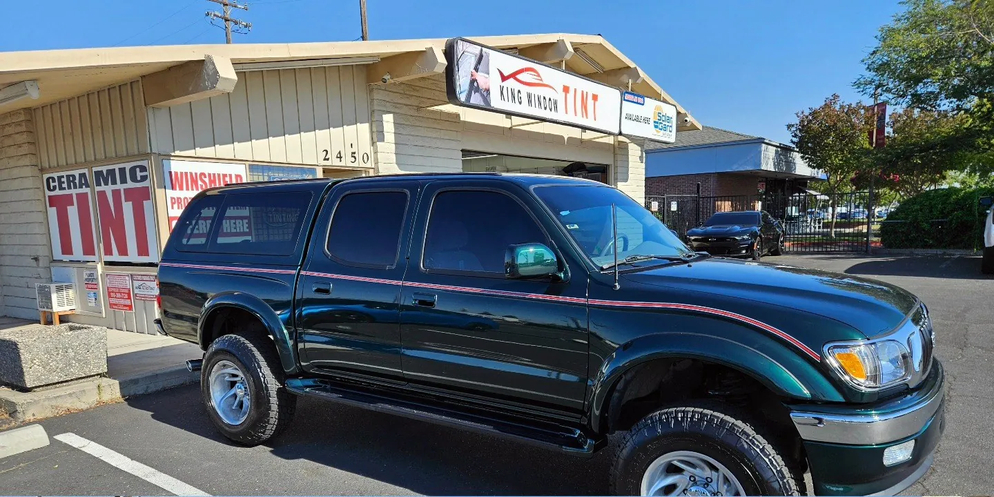 Dark green Toyota Tacoma with freshly tinted windows, in the King Window Tint parking lot on Fulton Avenue, Sacramento (first generation)