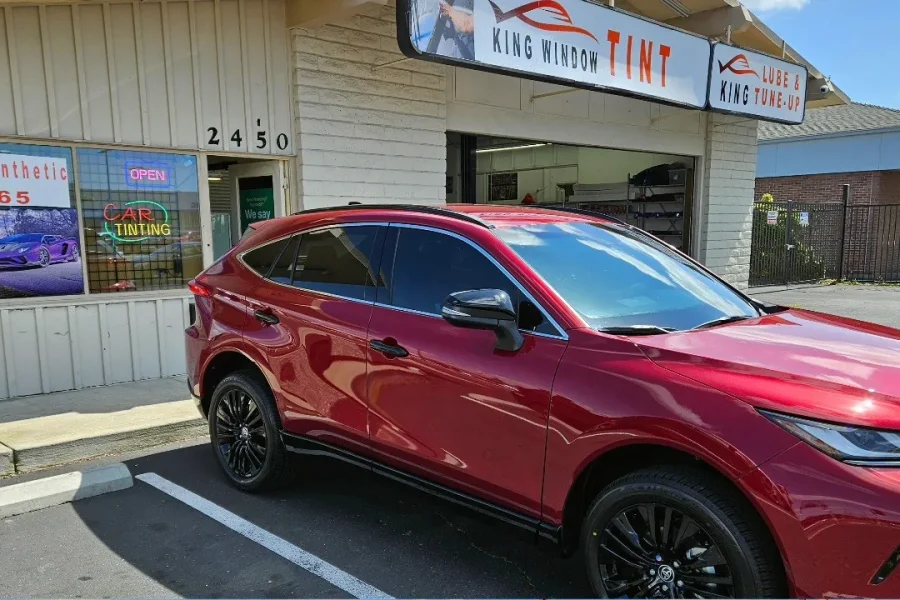 Red Toyota Venza with freshly tinted windows, beside the King Window Tint sign on Fulton Ave, Sacramento